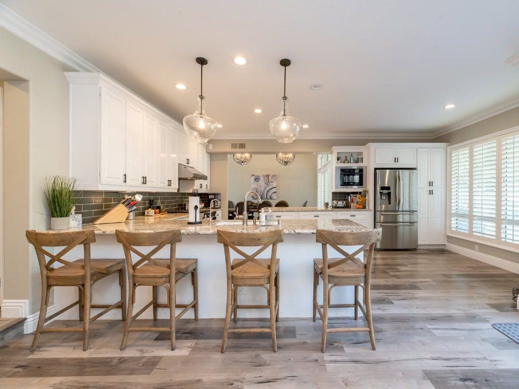 Bright and spacious kitchen featuring white cabinets, a large island with seating, pendant lighting, and stainless steel appliances, perfect for family gatherings and cooking enthusiasts.