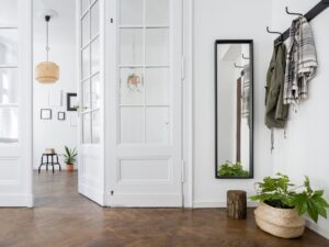 Stylish and functional entryway featuring coat hooks, a full-length mirror, and decorative plants, creating a welcoming and organized space.