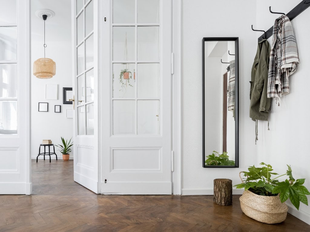 Stylish and functional entryway featuring coat hooks, a full-length mirror, and decorative plants, creating a welcoming and organized space.