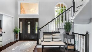 Stylish and welcoming home entrance featuring a staircase, black front door, and modern decor elements, creating a sophisticated and inviting entryway.